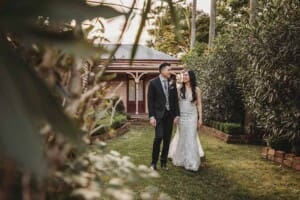 A couple stroll hand in hand through the garden at Burnham grove on the way to their wedding reception