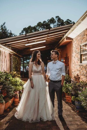 A backlit night photograph of a bride and groom standing outside their reception room at Gledswood