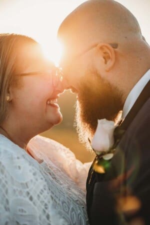A bride and groom stand close as the sun streams in from behind them at Ottimo House