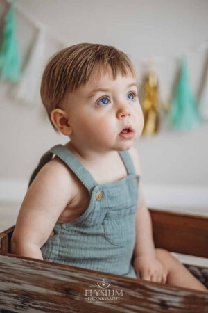 Portrait of a baby boy sitting on a crate in a bright studio