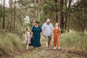 Parents stroll along a bush trail with their girls among the trees