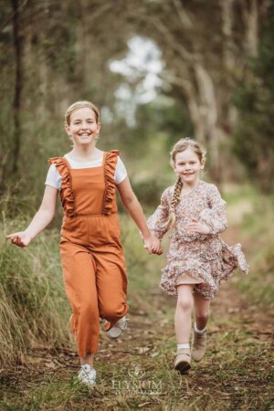 Girls giggle and run along a path holding hands