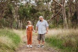A dad holds hands with his daughter as they stand on a track in a field