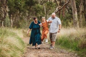 Parents walk along a track hand in hand with their daughter as they lift her up