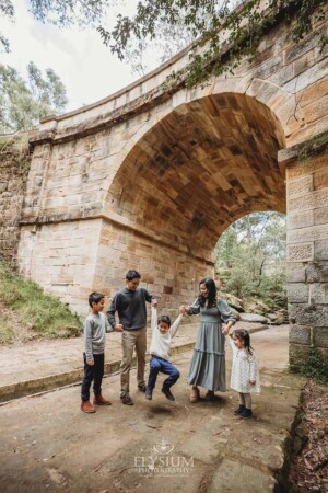 A couple swing their son between them standing under Lennox Bridge