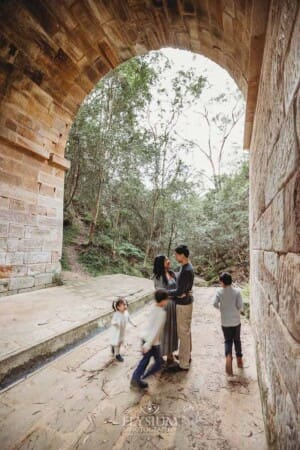 Kids run around their parents in a blur as they stand under a huge sandstone arch