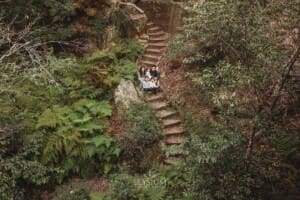 A family sit on the stone steps at Lennox Bridge surrounded by trees