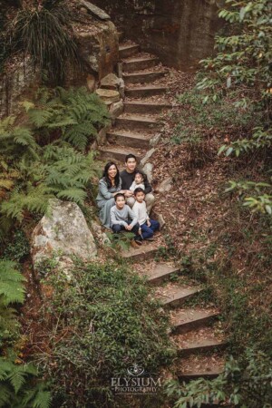 A family portrait of parents and their kids sitting on the stone stairs at Lennox Bridge