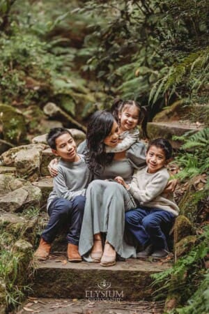 A mother sits on stone steps cuddling her three children
