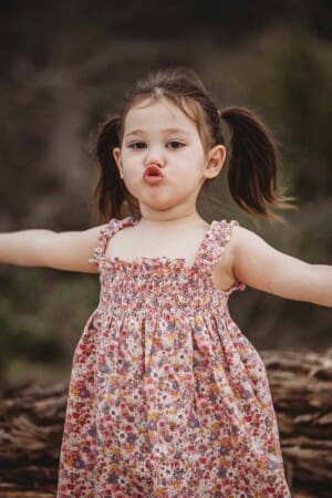 A little girl pulls a face with pouty lips as she stands on a beach