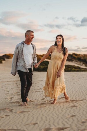 Parents walk along the top of the Cronulla Dunes at sunset as they laugh and hold hands