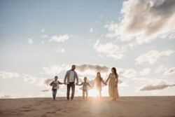 A family of five stand silhouetted against the golden sunset on top of Cronulla sand dunes