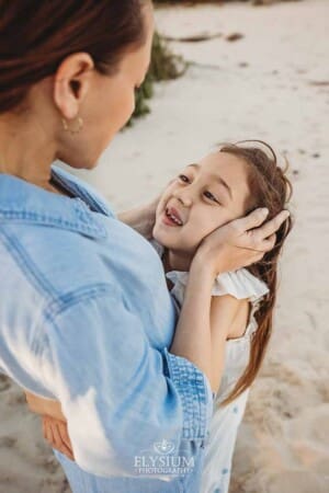 A mother holds her child's face in her hands and looks at her smiling