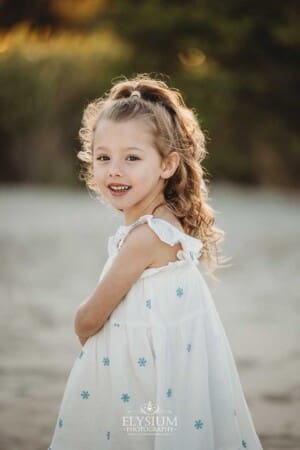 A little girl spins on the sand on a beach at sunset