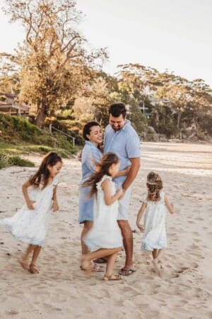 A family having fun on the beach with a couple watching their children run in circles around them