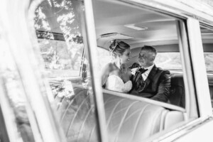 Newlyweds sit cuddling in the wedding car after their ceremony