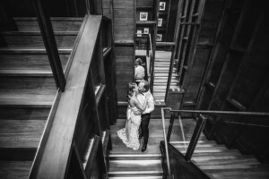 A bride and groom share a kiss in a staircase during their wedding reception