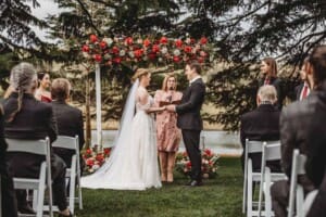 A bride and groom hold hands during the wedding ceremony at Bendooley surrounded by guests
