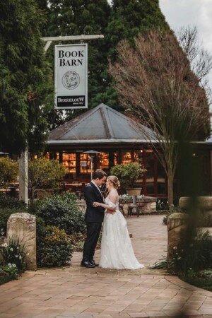 Newlyweds hug as they stand under the Bendooley Book Barn sign before entering the wedding reception