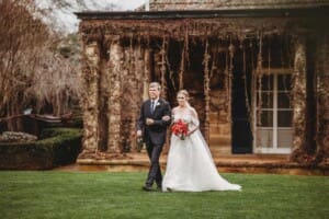 A bride and her father walk across the lawn at Bendooley towards the wedding ceremony