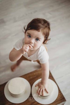 A baby boy stands next to a wooden crate and smashes his birthday cake