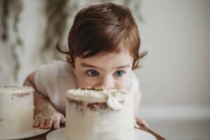 A baby boy smashes into his first birthday cake that sits on a timber box