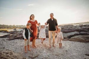 A family swing their youngest between them as they walk along a sandy beach