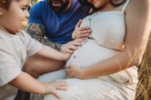 A little boy places his hands on his mum's pregnant belly