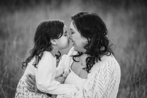 Little girl presses her nose against her mother's nose smiling during their fun‑filled outdoor family session in Ingleburn