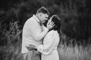 A man cups his wife's face with his hands as they share a tender moment during their Ingleburn family photo session