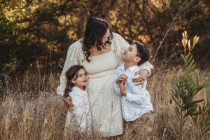 A mother hugs her children in warm golden light, a natural moment from their outdoor family photography session in Ingleburn
