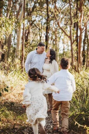 Children giggling as they run toward their parents in long grass, a fun‑filled highlight from their South West Sydney outdoor session