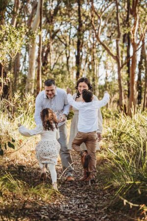 Children giggling as they run toward their parents in long grass, a fun‑filled highlight from their Ingleburn outdoor session