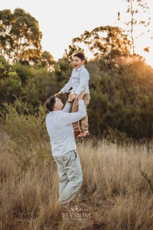 Parents lifting their child playfully in the field, an enjoyable and energetic moment from their outdoor family photography session