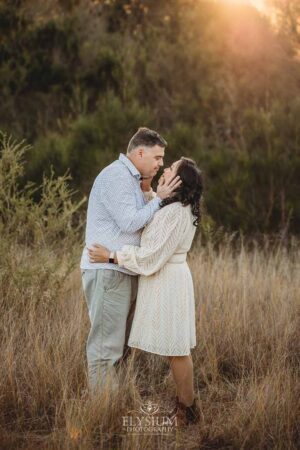 Parents sharing a quiet embrace in a grassy field, a warm and tender family photography scene at golden hour