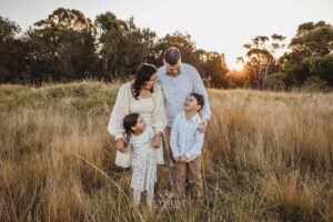 Family standing closely together in soft winter light, a warm and timeless sunset moment from their outdoor family photography session