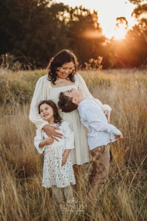 Parents cuddling their children in warm golden light, a natural and heartfelt moment from their outdoor family photography session
