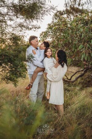 Family standing closely together in soft winter light, a warm and timeless sunset moment from their outdoor family photography session