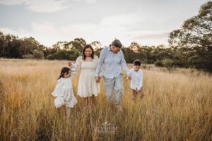 Family walking hand‑in‑hand through the field at sunset, a relaxed and enjoyable moment captured by a family photographer