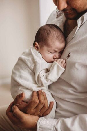 Father holding his newborn during a calm photo session in the Ingleburn natural‑light studio