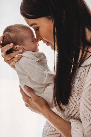 Mother holding her newborn’s face close to hers in soft natural light at the Ingleburn studio