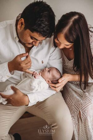Parents cuddling their newborn in soft studio light, photographed by an Ingleburn newborn photographer