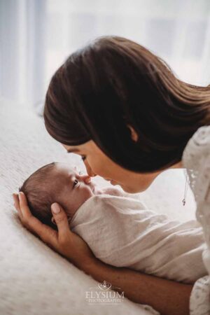 Close view of a newborn laying peacefully in a mother’s arms during a studio session in Ingleburn