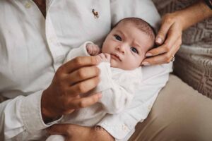 Close view of parents holding their newborn between them during a studio session in Ingleburn